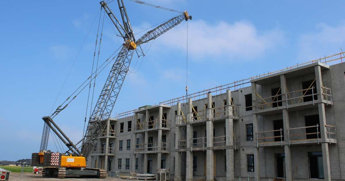 crain lifting concrete a slab onto a concrete building 